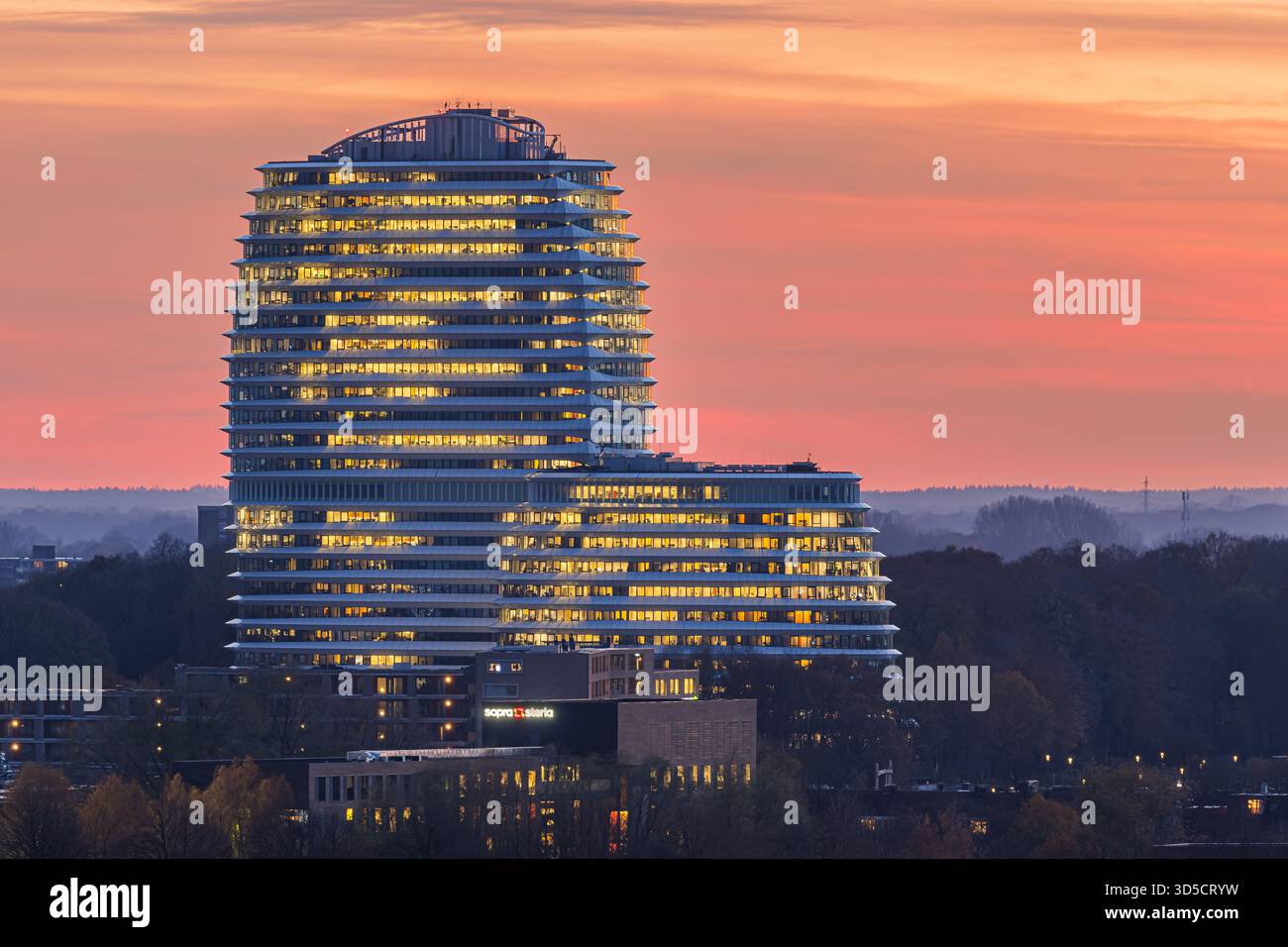 Das ikonische DUO-Gebäude in Groningen, Niederlande, wird vom warmen Glanz des Sonnenuntergangs beleuchtet. Sanfte Orange-, Rosa- und Violetöne füllen den Himmel A Stockfoto