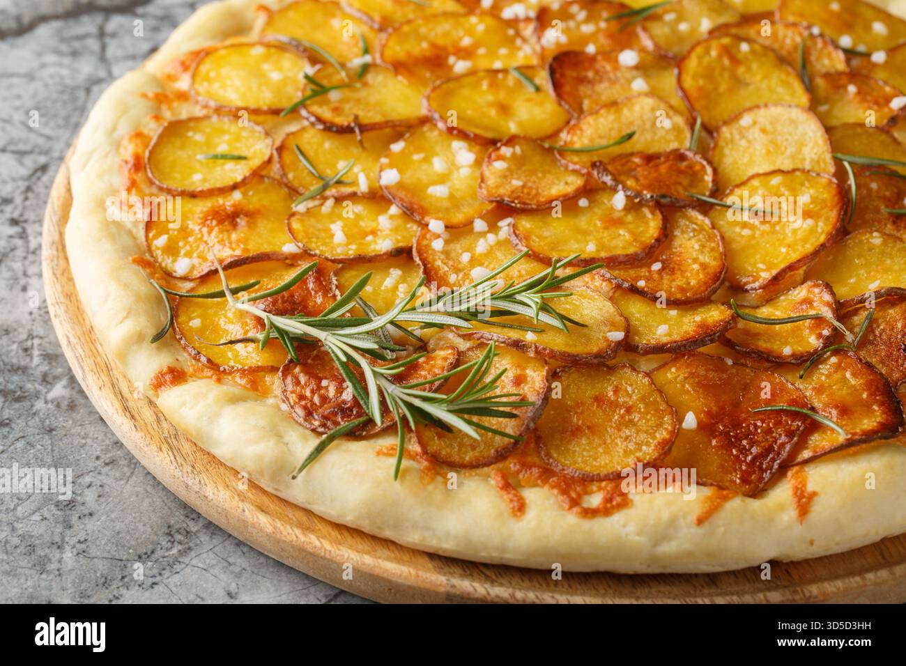 Frisch gebackene Pizza mit Kartoffelgemüse und Rosmarin Nahaufnahme auf dem Holzbrett auf dem Tisch. Horizontal Stockfoto
