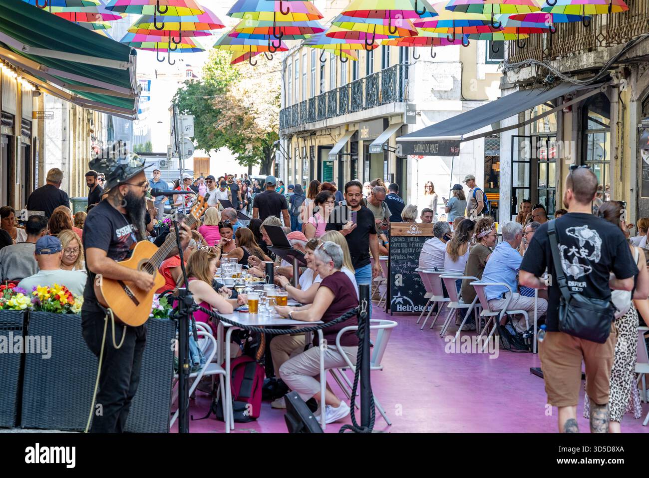Rosa Straße Lissabon, offiziell Rua Nova do Carvalho genannt, Straße mit rosa Pflaster und mehrfarbigen Regenschirmen, die darüber hängen, Portugal, Europa Stockfoto