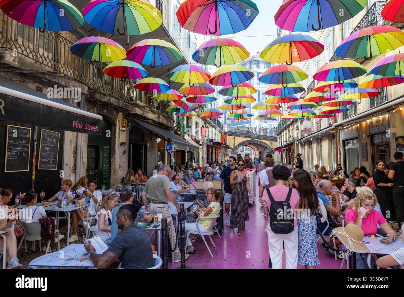 Rosa Straße Lissabon, offiziell Rua Nova do Carvalho genannt, Straße mit rosa Pflaster und mehrfarbigen Regenschirmen, die darüber hängen, Portugal, Europa Stockfoto