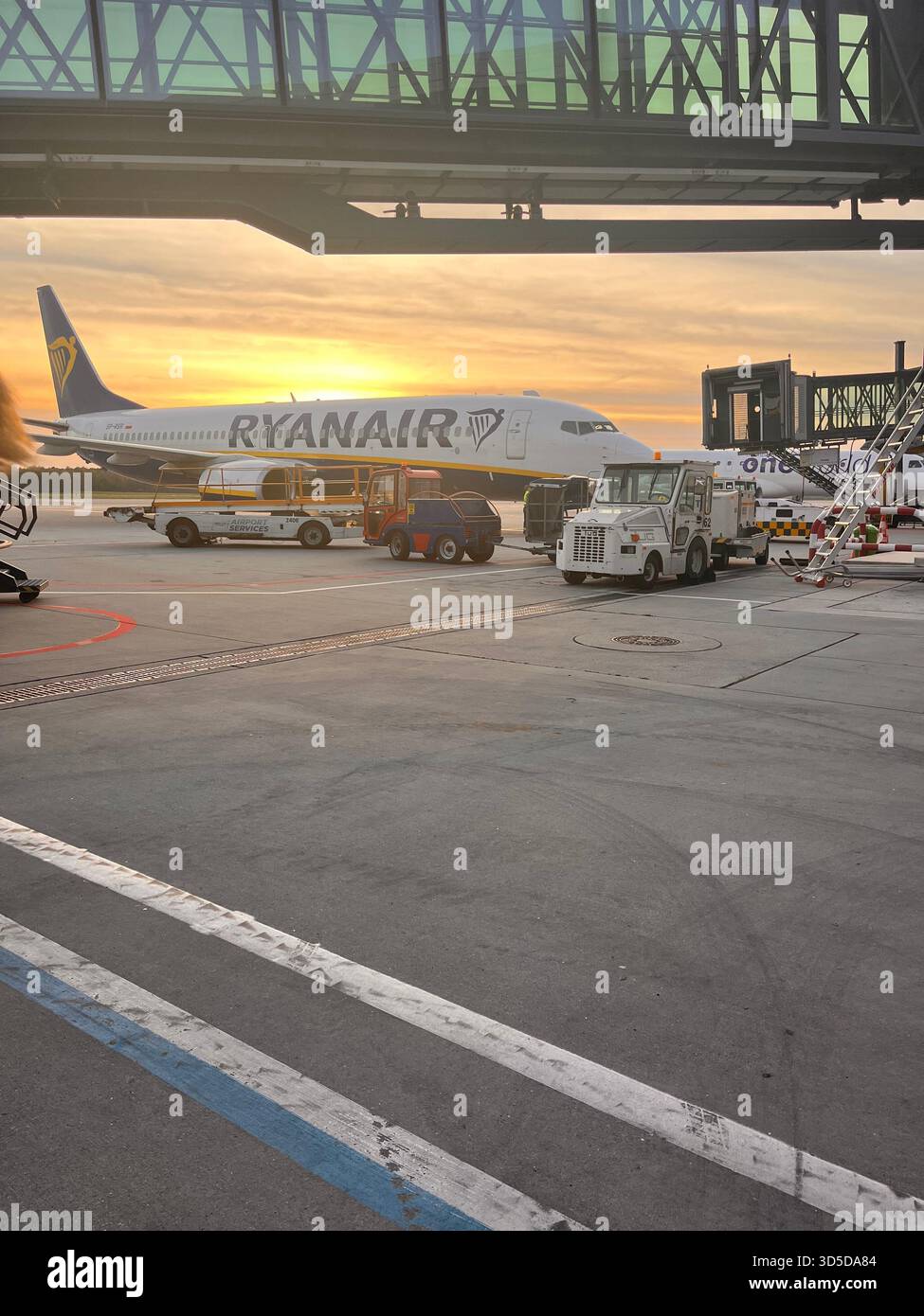 Ryanair Passagierflugzeug parkte während des Sonnenuntergangs am Leeds Bradford Airport, England, mit Bodenfahrzeugen. Stockfoto