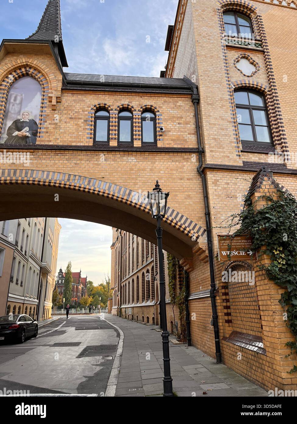 Malerische Straße mit historischem Backsteinbogen und Laterne in der Altstadt von Wrocław, Polen, im warmen Abendlicht. - Smartphone-aufgenommenes Stockfoto