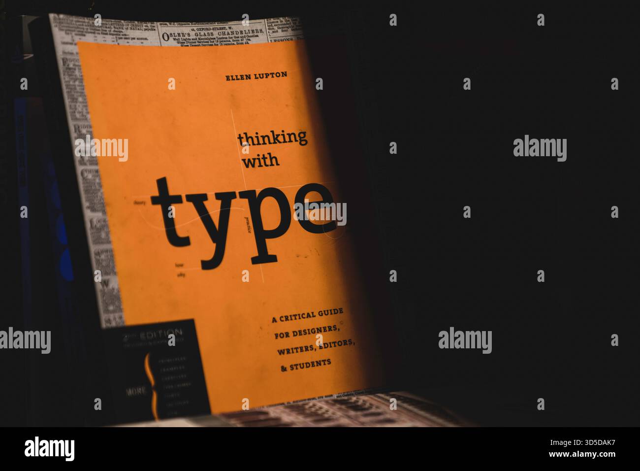 Eine dramatische Aufnahme des Buchumschlags „Thinking with Type“ bei schlechten Lichtverhältnissen mit Schwerpunkt auf Typografie und grafischen Designelementen. Stockfoto