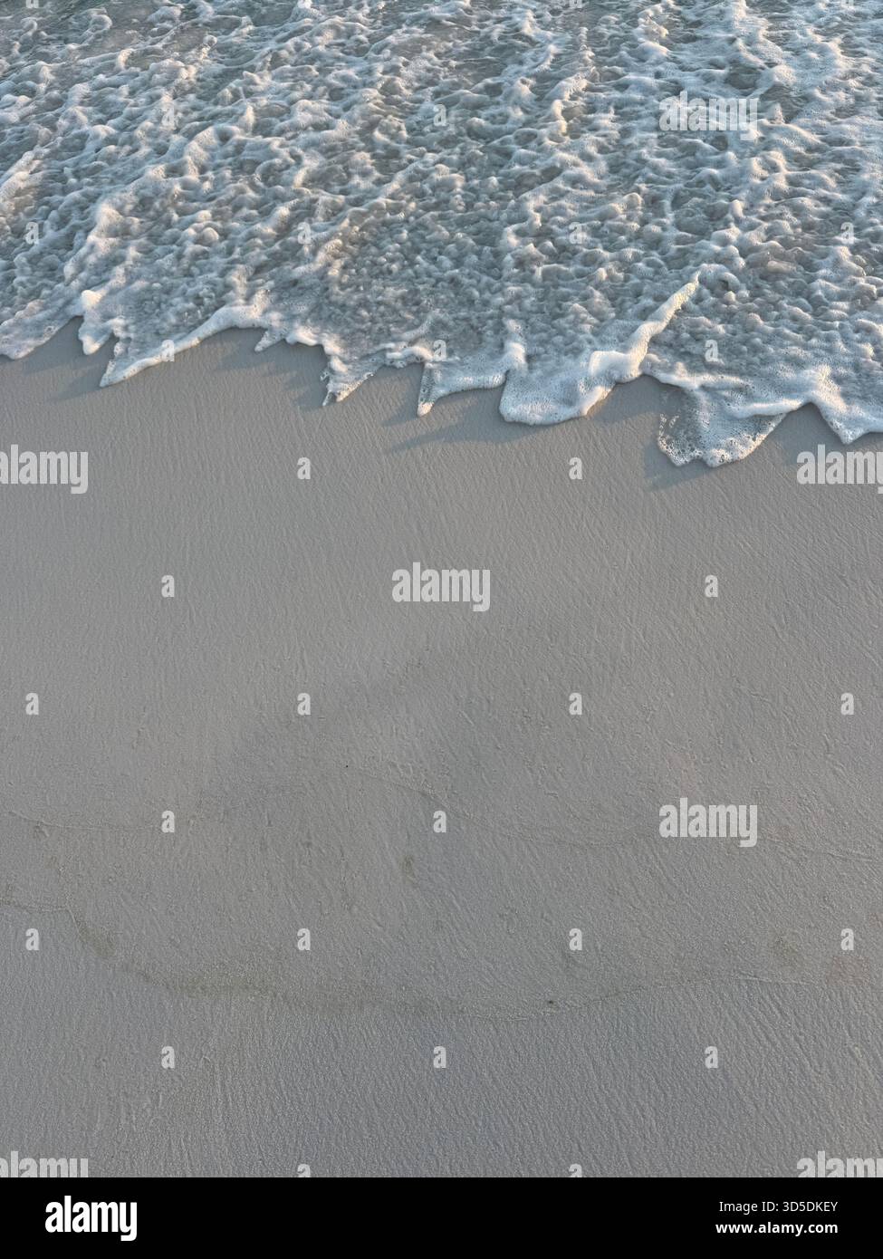 Abstrakter Hintergrund von schaumiger Strandwelle und Sand mit Kopierraum - Smartphone-aufgenommenes Stockfoto