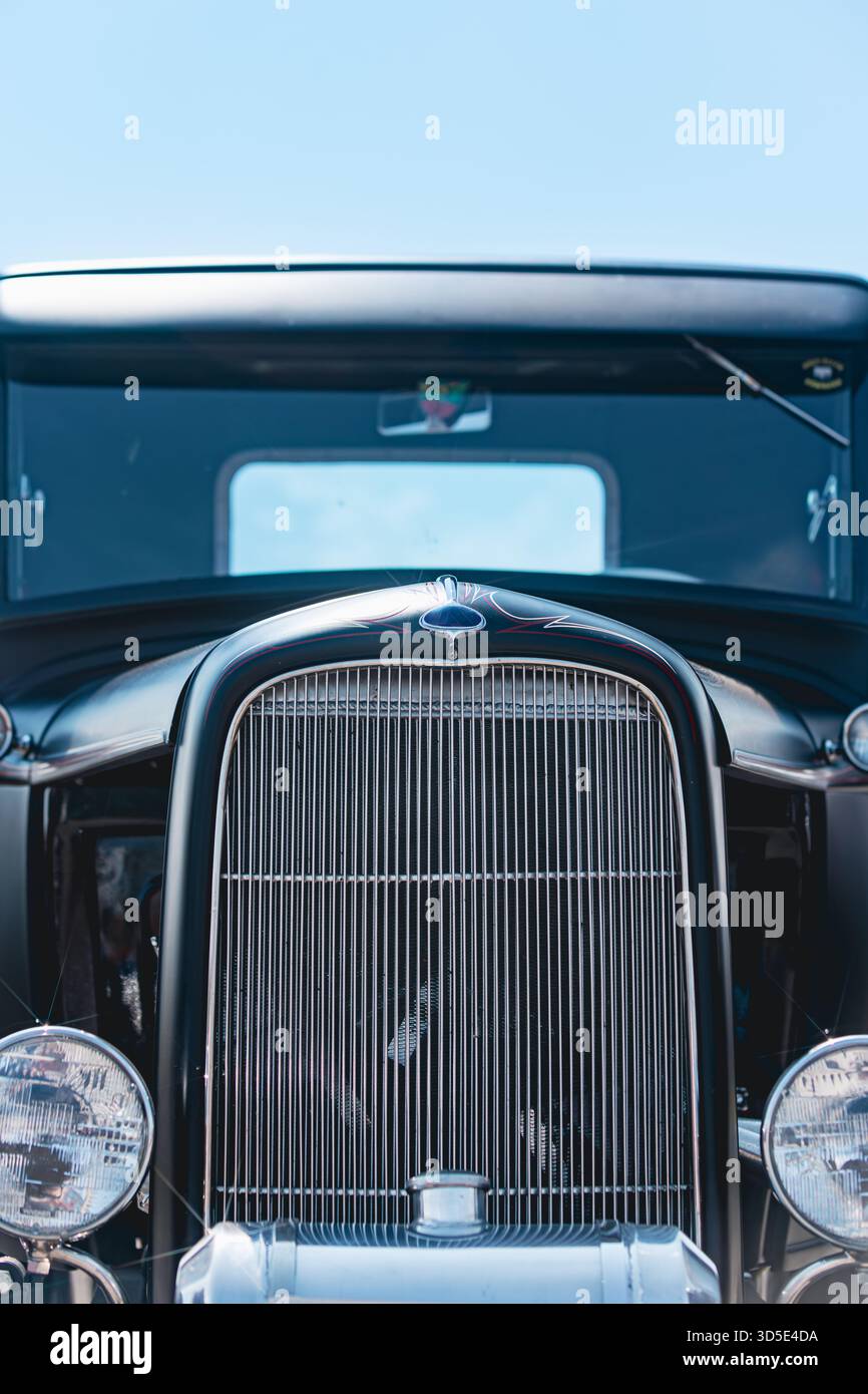 Nahaufnahme des restaurierten, blauen Hot Rod-Kühlergrills und der Verzierung der verchromten Motorhaube. Vertikale verchromte Gitterleisten, abgerundete Kotflügel, Scheinwerfer Stockfoto