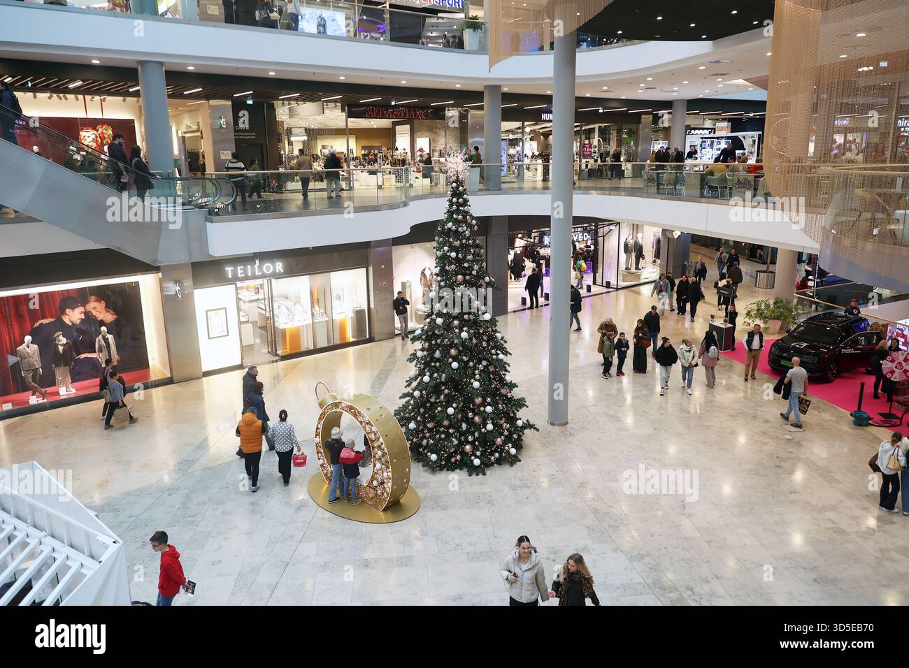 Menschen, die während der Feiertagszeit in einem Einkaufszentrum einkaufen, mit einem großen, geschmückten Weihnachtsbaum in Budapest, Ungarn Stockfoto