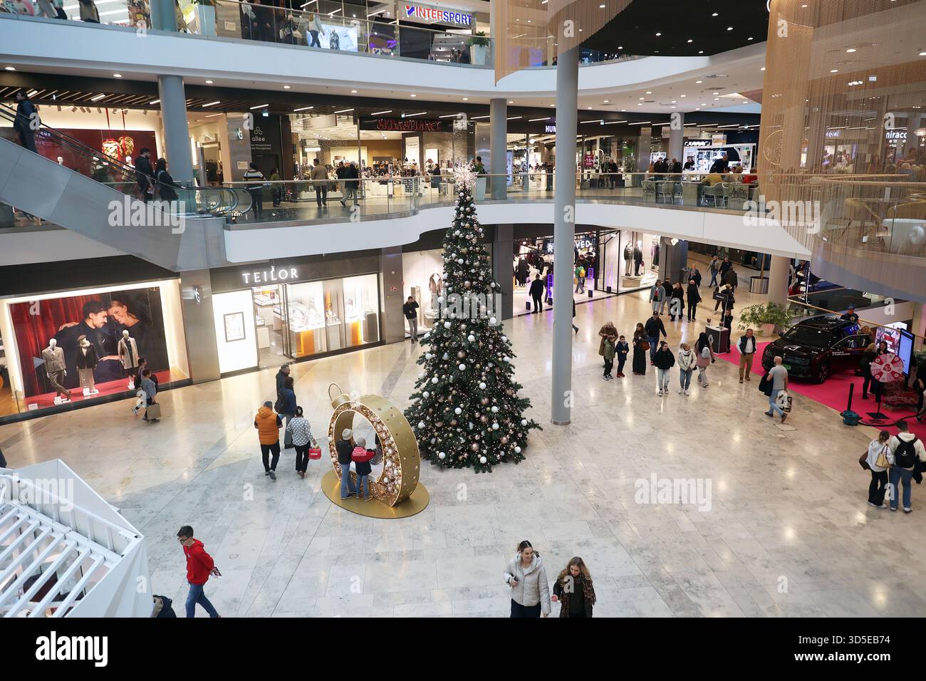 Menschen, die während der Feiertagszeit in einem Einkaufszentrum einkaufen, mit einem großen, geschmückten Weihnachtsbaum in Budapest, Ungarn Stockfoto