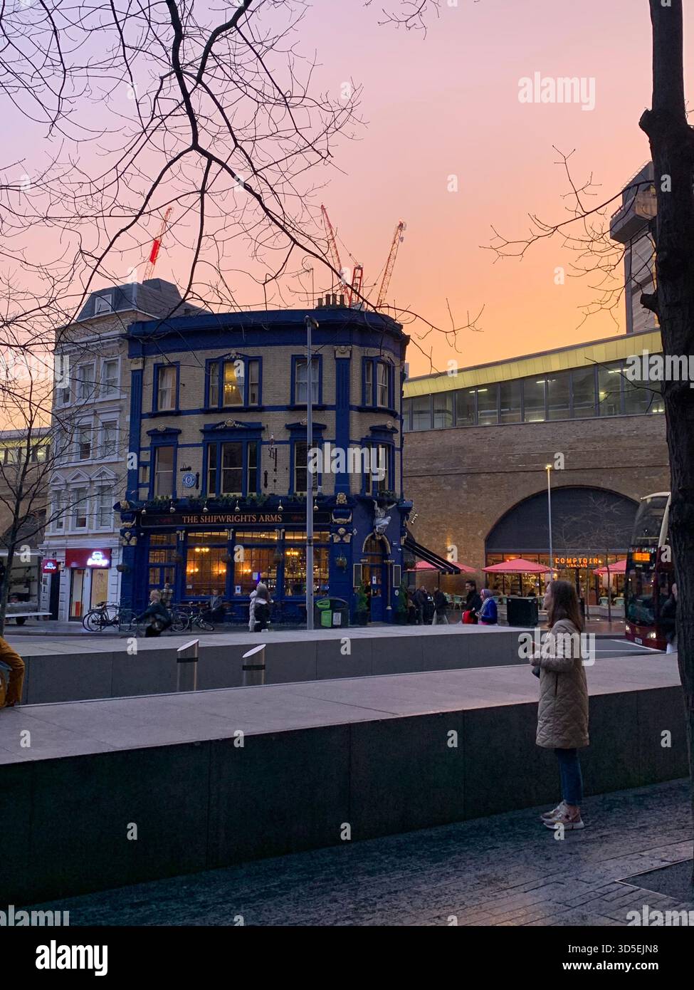 Warmer Sonnenuntergangshimmel über der Themse mit Silhouetten von Londoner Gebäuden und Reflexionen auf dem Wasser. - Smartphone-aufgenommenes Stockfoto