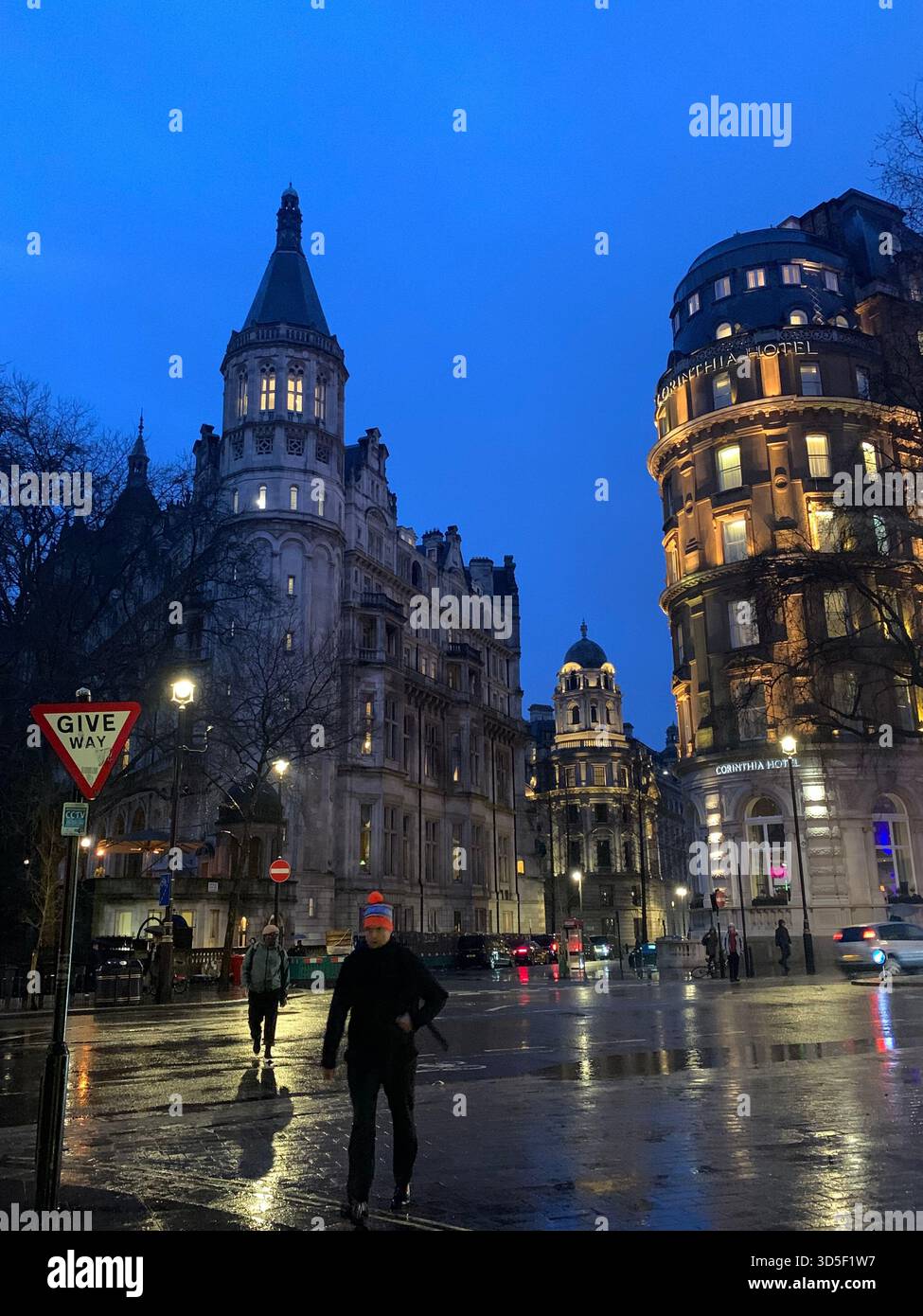 Abendliche Straßenszene im Londoner West End mit beleuchteten historischen Gebäuden und feuchten Straßen nach Regen. - Smartphone-aufgenommenes Stockfoto