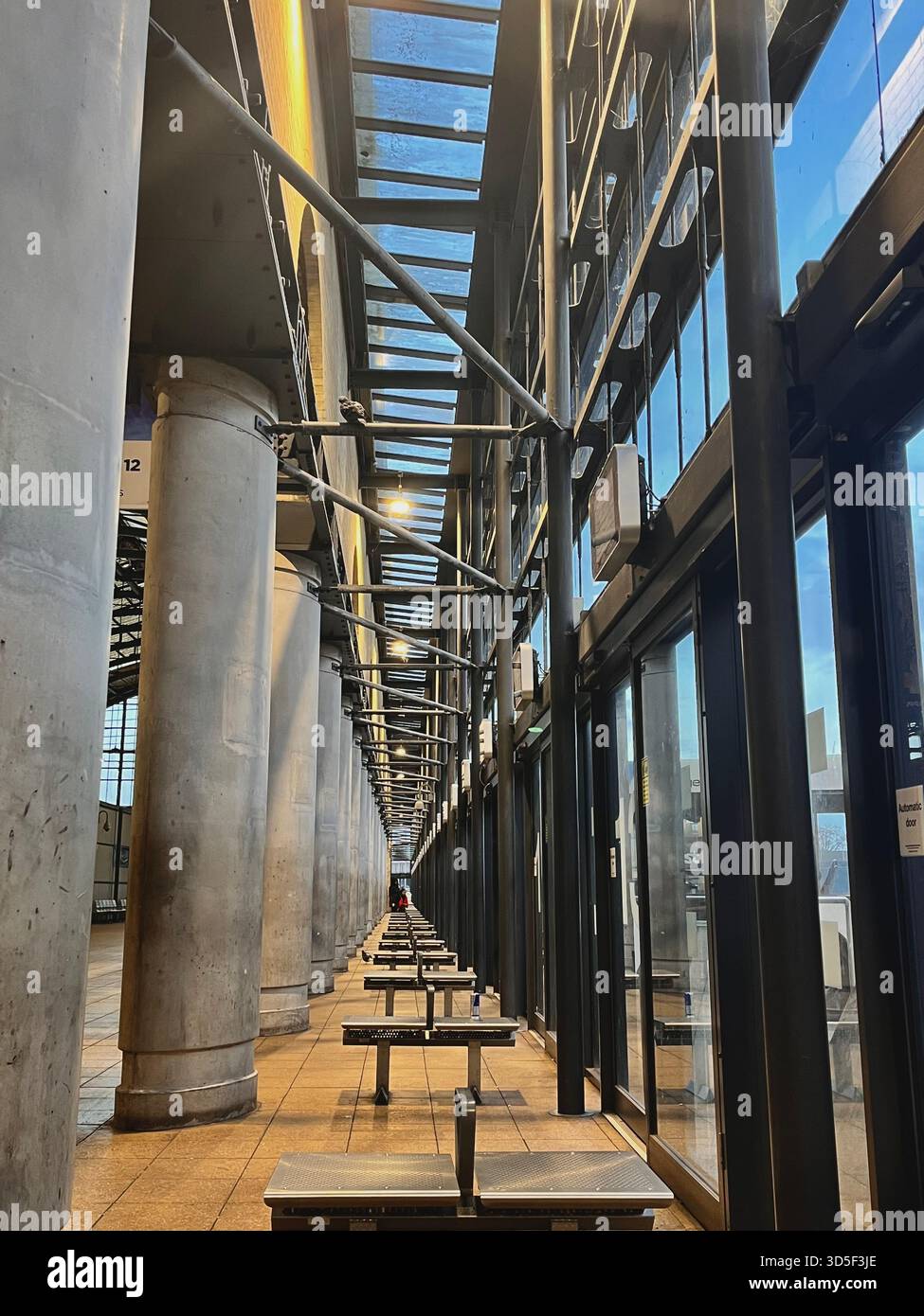 Moderner architektonischer Korridor mit Glaswänden und strukturellen Säulen in Hull, England. Saubere Linien, Symmetrie - Smartphone-aufgenommenes Stockfoto