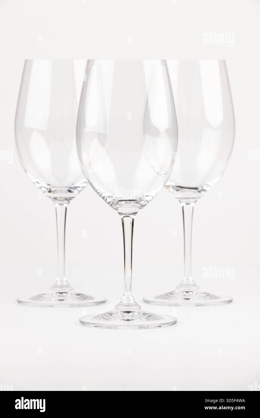 Drei elegante, transparente Weingläser mit langen Stielen vor neutralem Hintergrund Stockfoto