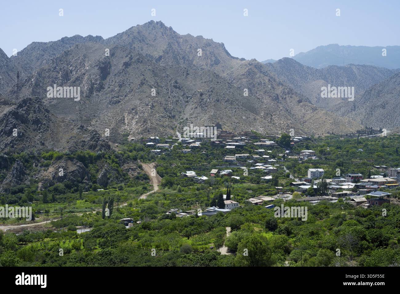 Bergdorf mit üppiger Vegetation, umgeben von imposanten Bergen und klarem blauen Himmel, Meghri, Provinz Syunik, Syunik, nicht weit von der Grenze W Stockfoto
