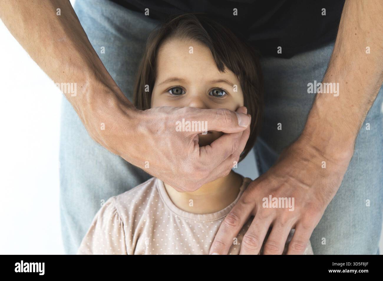 Männliche Hand bedeckt Mund von Kind Mädchen 2-3 Jahre alt, Nahaufnahme, Kindesmisshandlung, Konzept häuslicher Gewalt, Kinderschutz Stockfoto