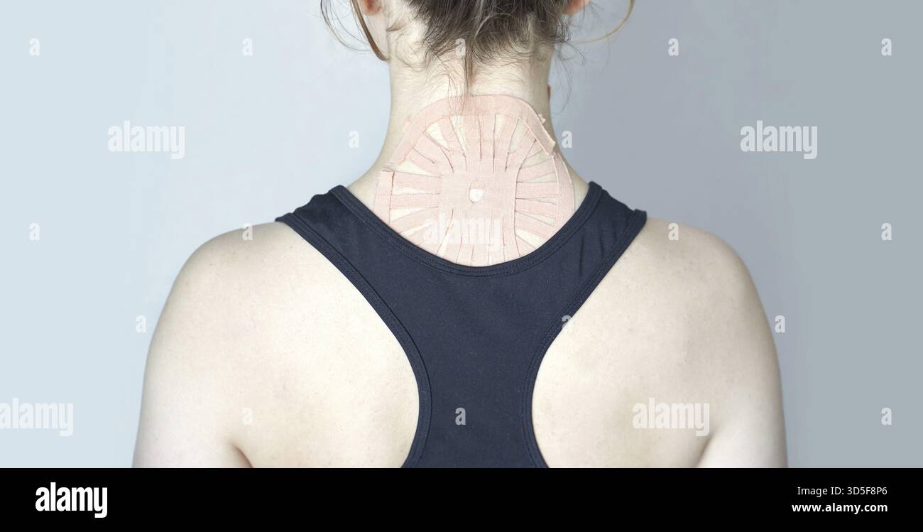 Kaukasische Frau mit therapeutischem Kinesiologieband am oberen Rücken zur Muskelunterstützung Stockfoto