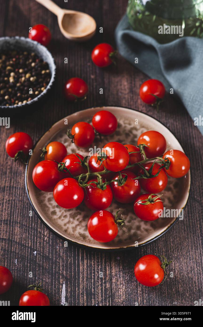 Teller mit frischen Kirschtomaten auf einem Holztisch mit vertikaler Ansicht Stockfoto