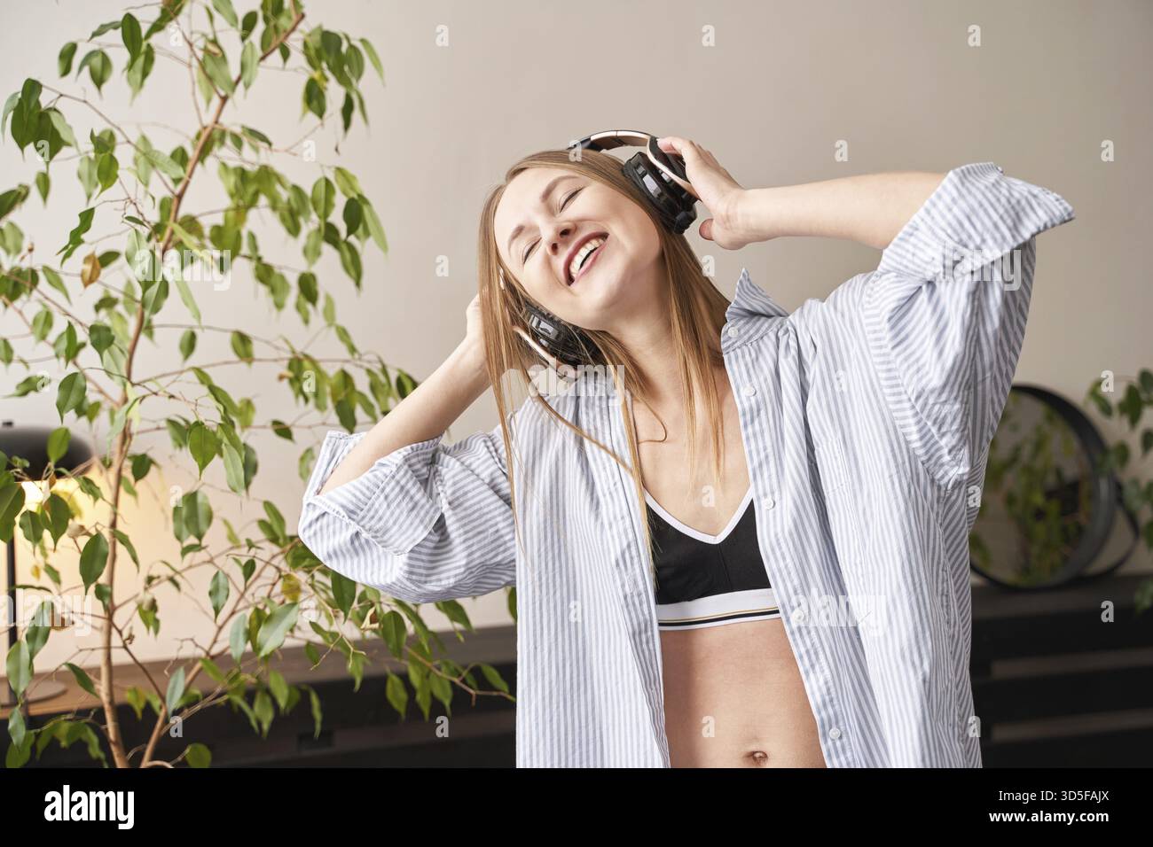 Die junge Frau singt zu Hause. Die Texte des Hauses tanzen. Lustiges Lied. Unabhängiges Frauenporträt. Allein zu Hause. Quarantäneaktion sitzend. Fröhliche Entspannung Stockfoto
