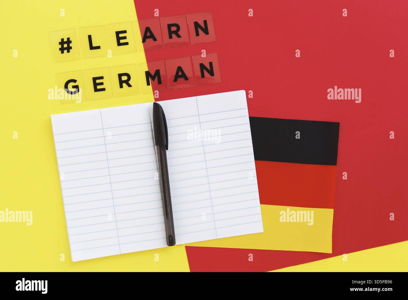 Rot-gelber Hintergrund, Inschrift mit Hashtag Deutsch lernen, Notizbuch und Stift, Flagge Deutschlands, Fremdsprachenlernkonzept, Online-Ausbildung Stockfoto