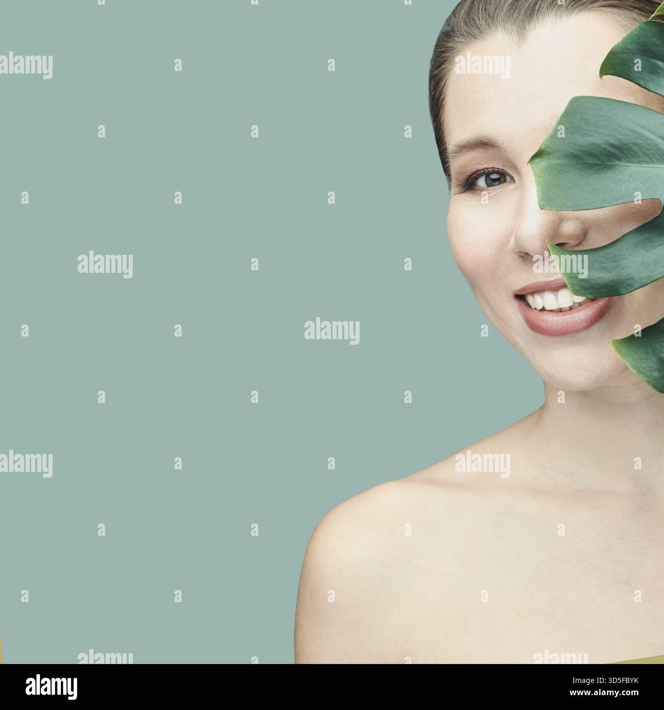 Junge Frau. Lächelnd mit Monstera-Blatt. Modell im Studio. Kosmetologische Gesundheitskonzepte. Wunderschönes tropisches Blatt. Stomatologische medizinische Behandlung. Innengewinde p Stockfoto