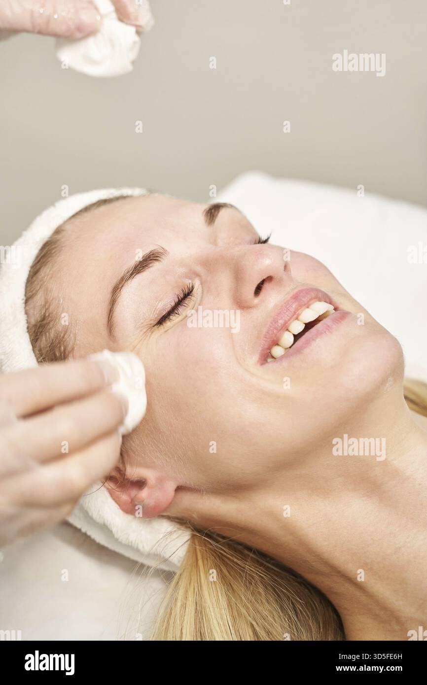 Im Spa-Salon wird eine Massage mit lächelndem Gesicht vorbereitet. Arzthände. Hübsche Patientin. Schönheitsbehandlung. Gesundheit Hautverfahren. Der Kopf der jungen Frau. Reinigung Re Stockfoto