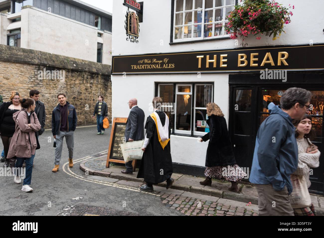 Ein Absolvent der Oxford University, der am Bear Inn Pub und Restaurant in Oxford, Großbritannien, vorbeiläuft Stockfoto