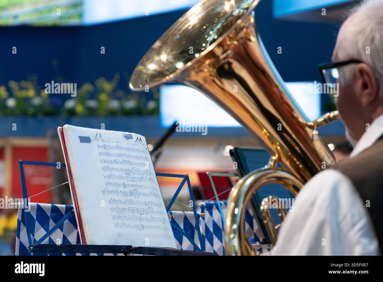 Berlin, Deutschland - 22. Januar 2024: Musiker spielt Tuba, während Notenblätter in lebendiger Performance auf dem Stand stehen. Stockfoto