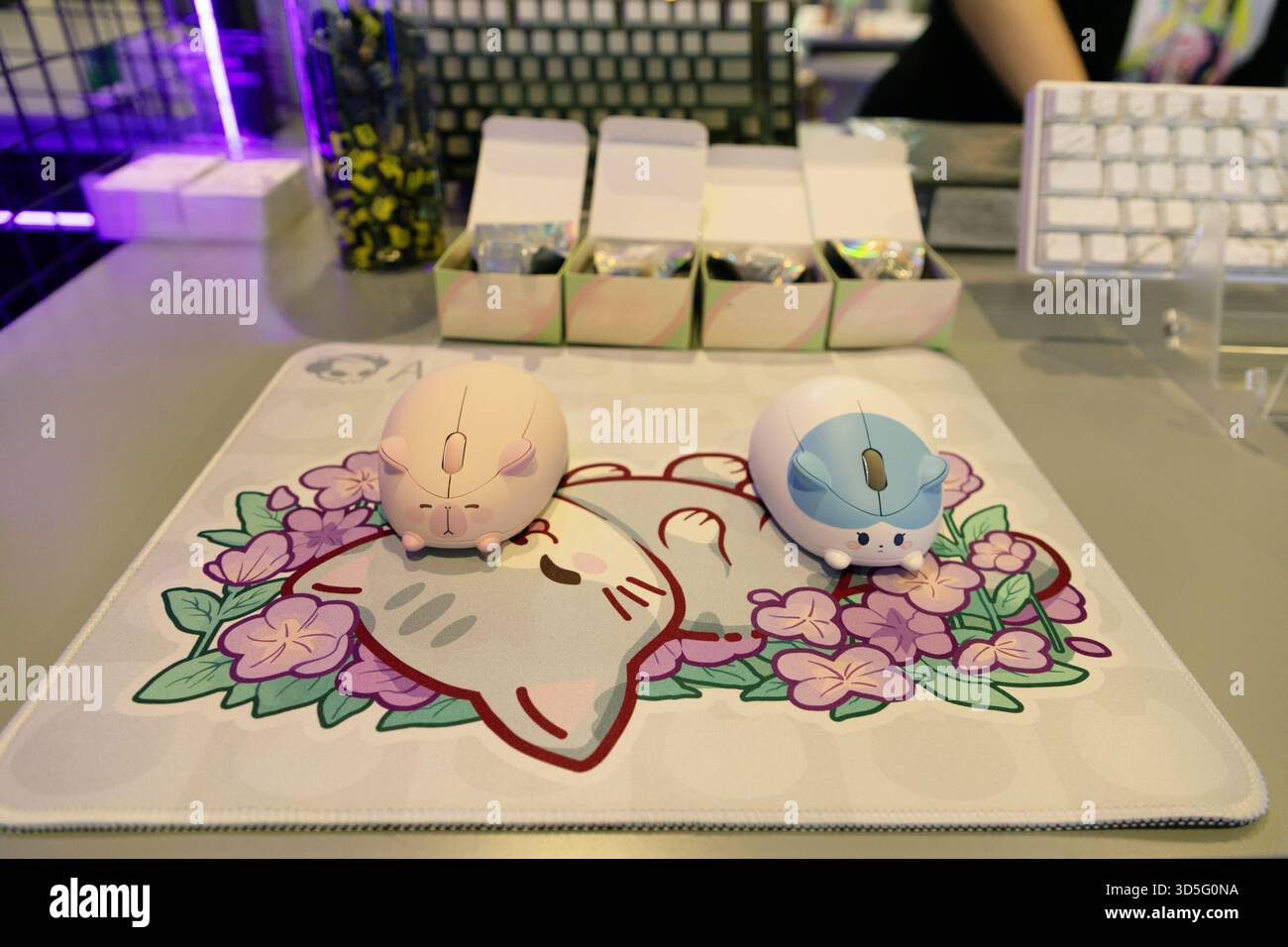 Berlin, Deutschland - 09. September 2025: IFA.Berlin. Niedliche Computermaus in Katzenform liegt auf einem Mousepad mit Blumenmousepad mit farbenfrohen Hintergrundelementen auf Stockfoto