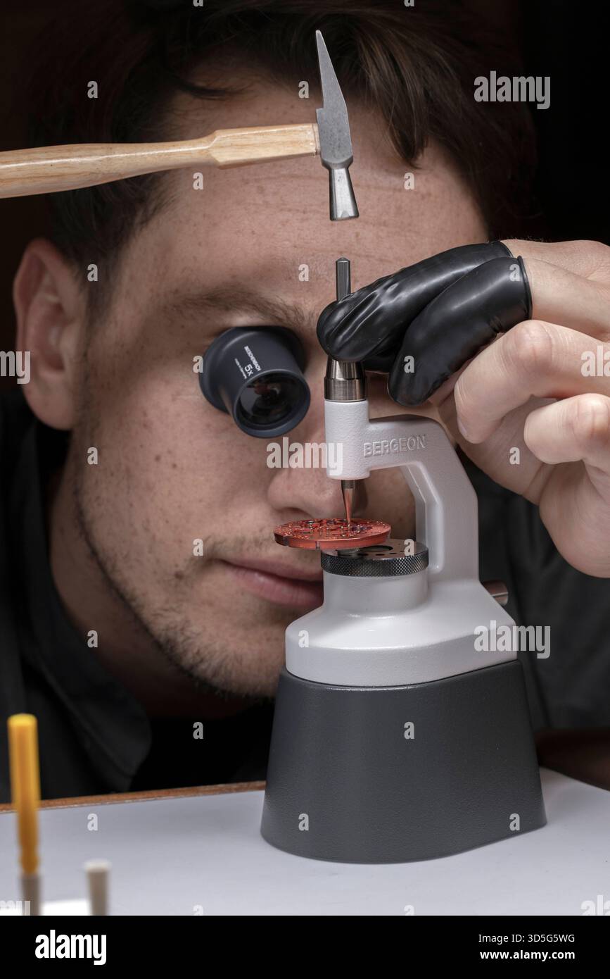 Männlicher Uhrmacher, der mit Juwelierwerkzeug am Uhrwerk arbeitet Stockfoto