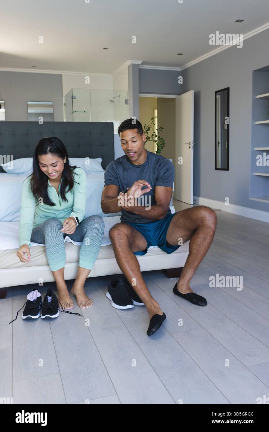 Afroamerikanisches Paar bereitet sich auf das Training zu Hause vor, lächelt und zieht Schuhe an Stockfoto