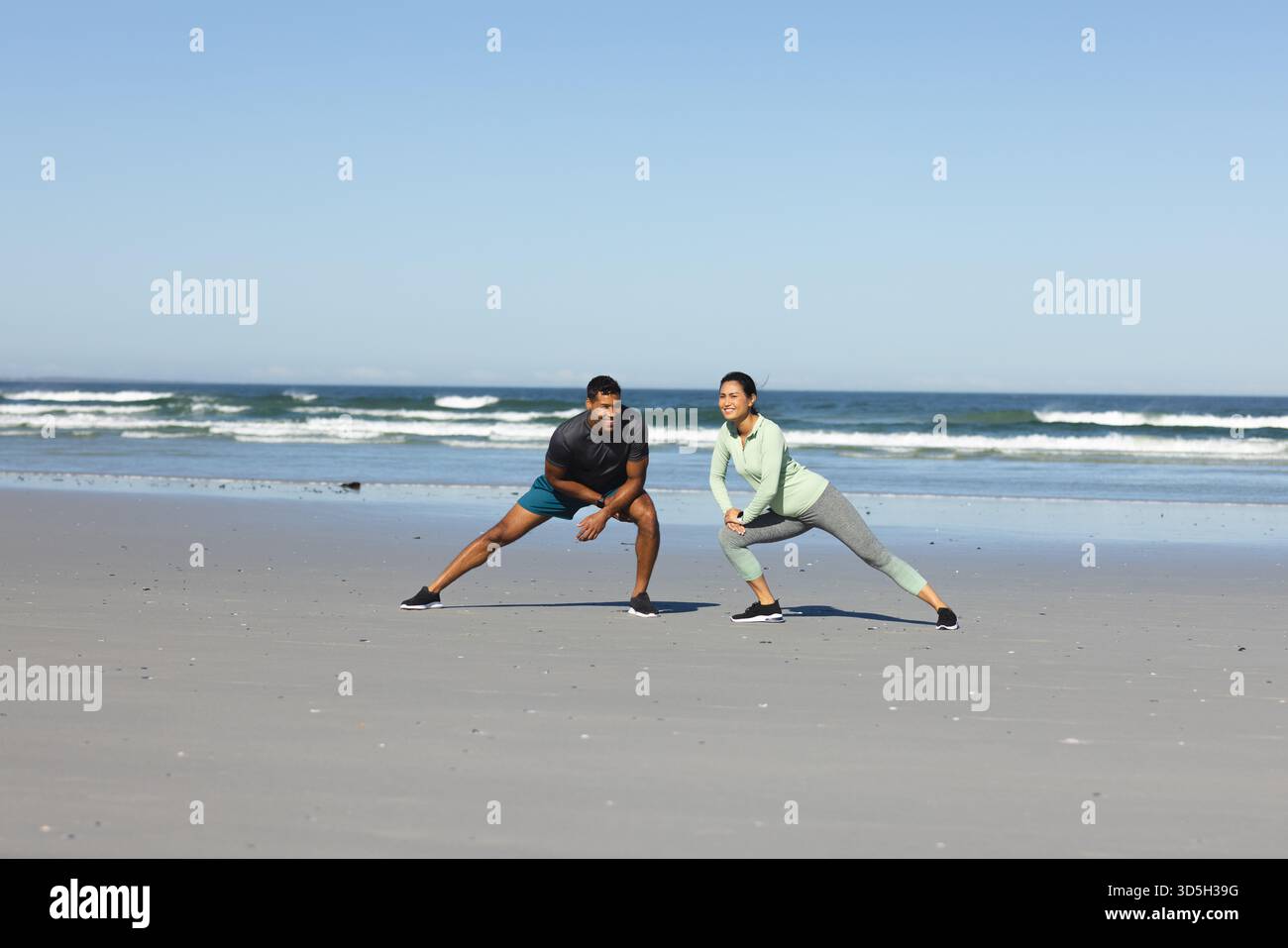 Paare trainieren am Strand, Strecken Beine und genießen sonniges Workout am Morgen Stockfoto