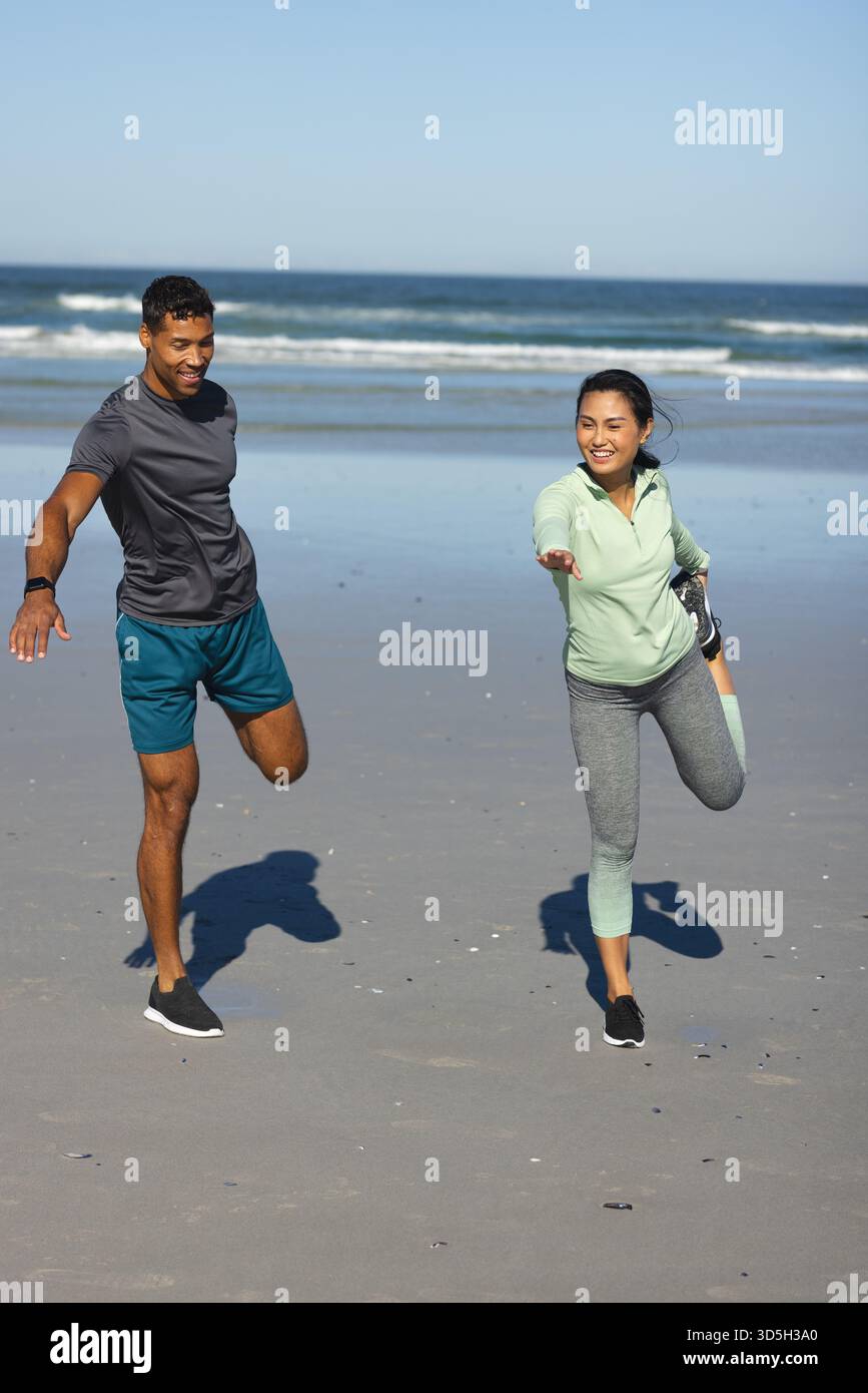 Paare trainieren am Strand, Strecken Beine und genießen sonniges Workout am Morgen Stockfoto