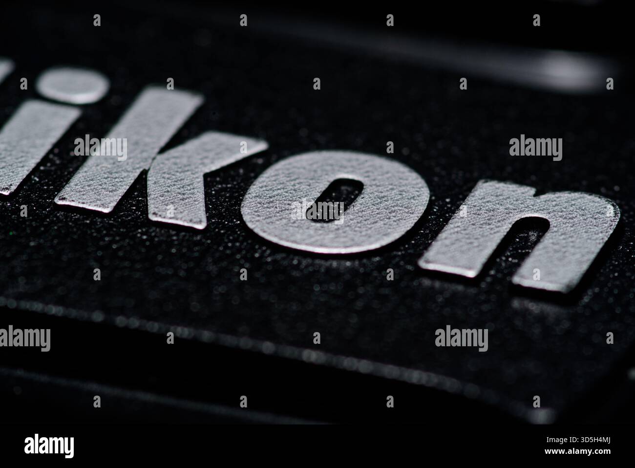 Makroaufnahme des Nikon Logos in weißen Buchstaben auf einer strukturierten schwarzen Oberfläche, die die Metallic-Oberfläche und Produktdetails der Marke unterstreicht. Stockfoto