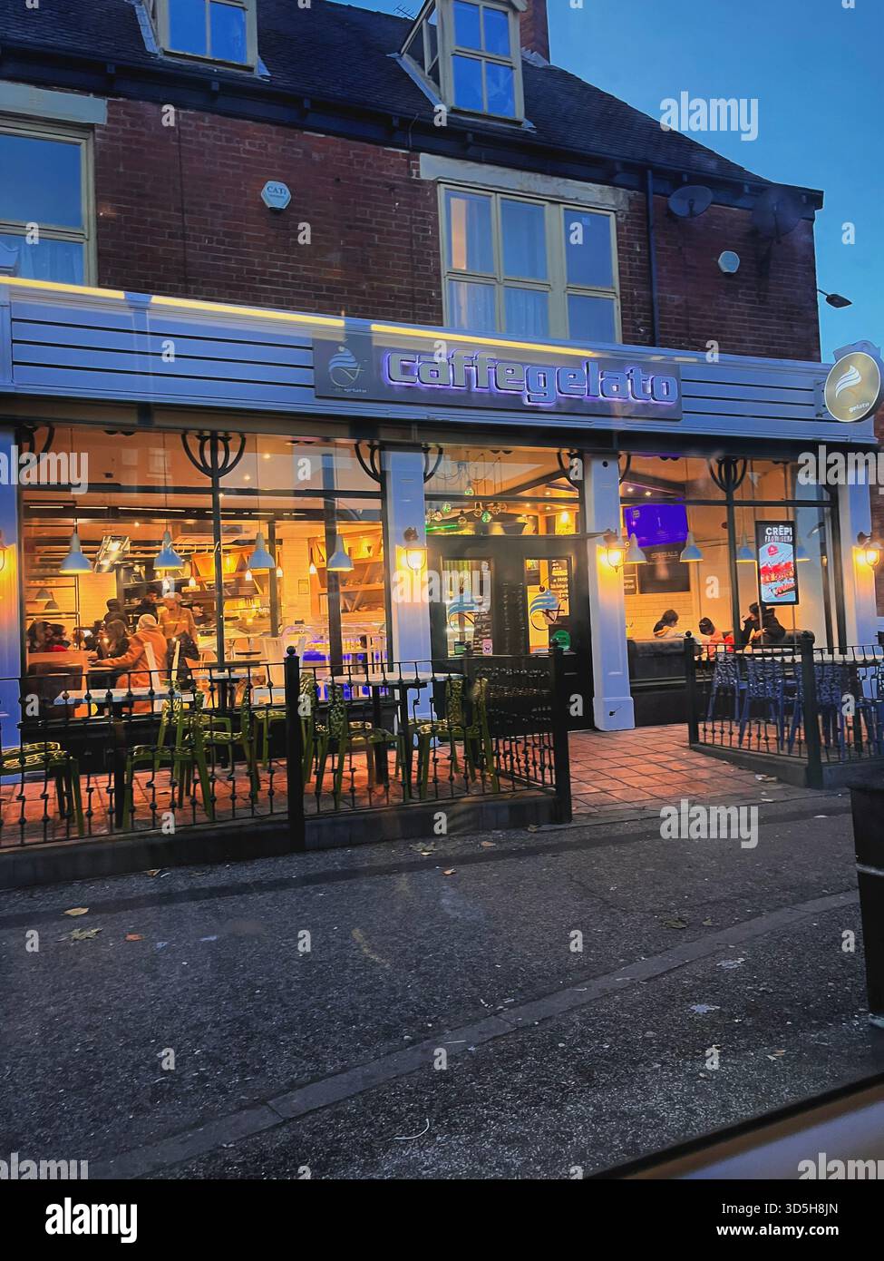 Außenansicht eines lokalen Cafés in der Abenddämmerung in Hull, England, mit warmen Innenbeleuchtung und einladender Atmosphäre. Urbane Lifestyle-Szene, die kleine Unternehmen repräsentiert - Smartphone-aufgenommenes Stockfoto