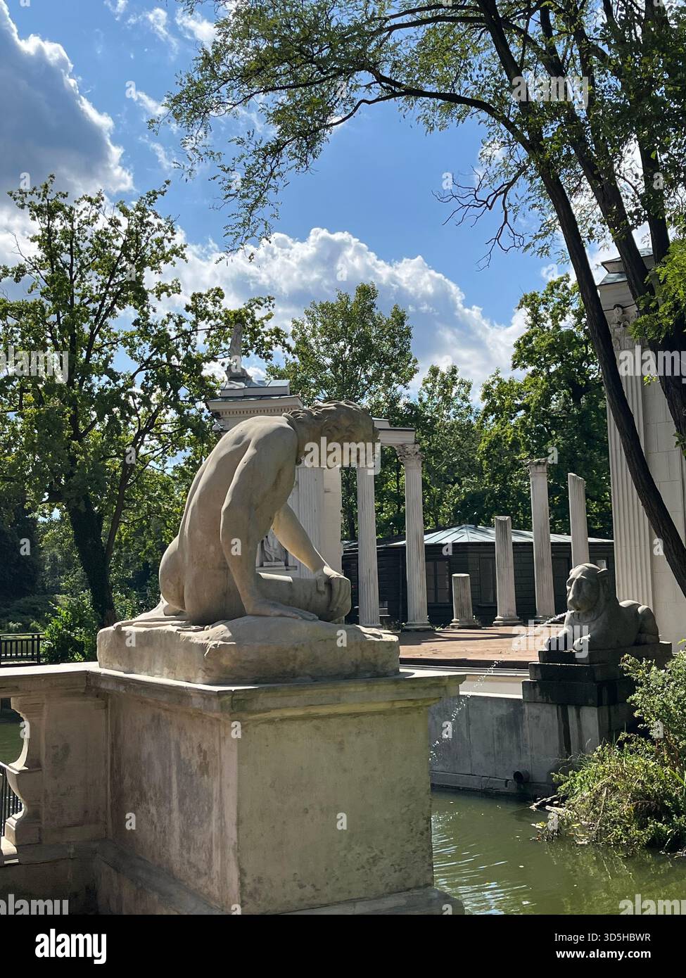 Brunnen mit Steinskulpturen in einem grünen Park in Warschau. Öffentliches Kunstdenkmal umgeben von Natur in Polens Hauptstadt. - Smartphone-aufgenommenes Stockfoto
