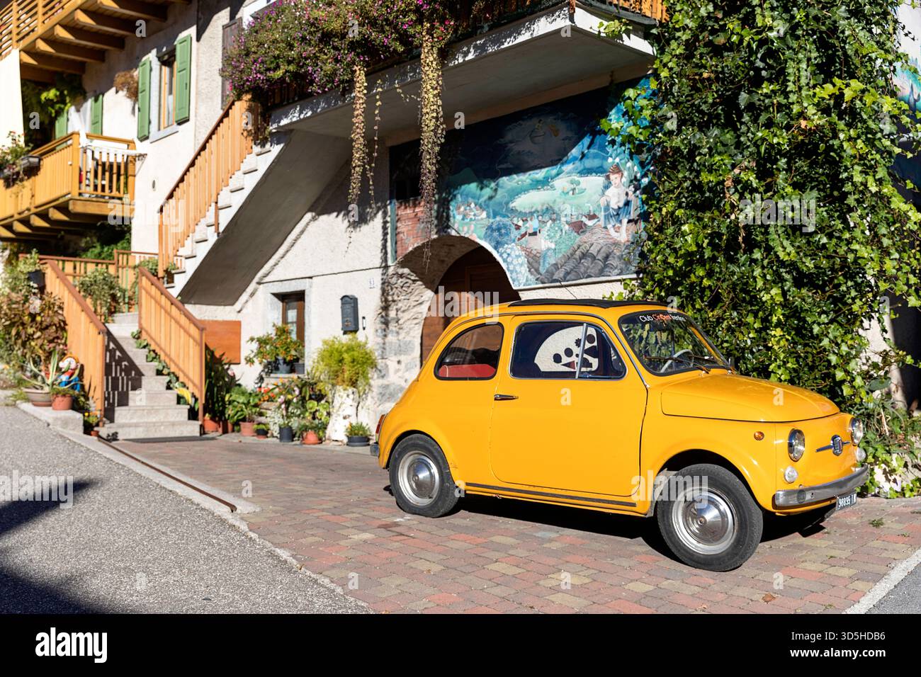 Gelbes FIAT 500 im alten Stil, das vor den traditionellen alten Häusern des Dorfes Rango in der Provinz Trient in der Nähe des Gardasees in Italien geparkt ist Stockfoto