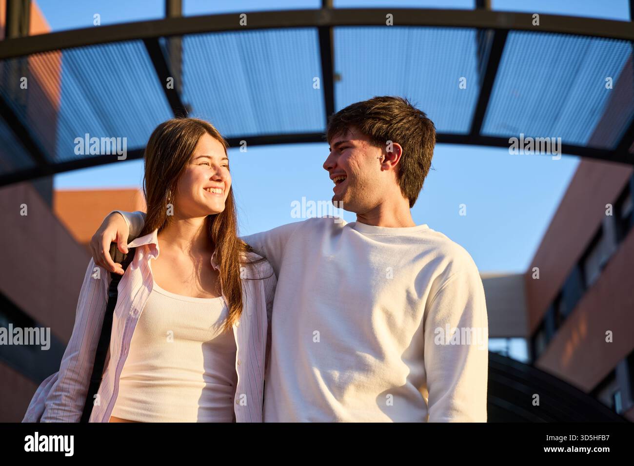 Glückliche Studenten, die sich auf dem Universitätscampus tummeln, einen sonnigen Tag im Freien genießen, Freundschaft und gute Zeiten teilen Stockfoto