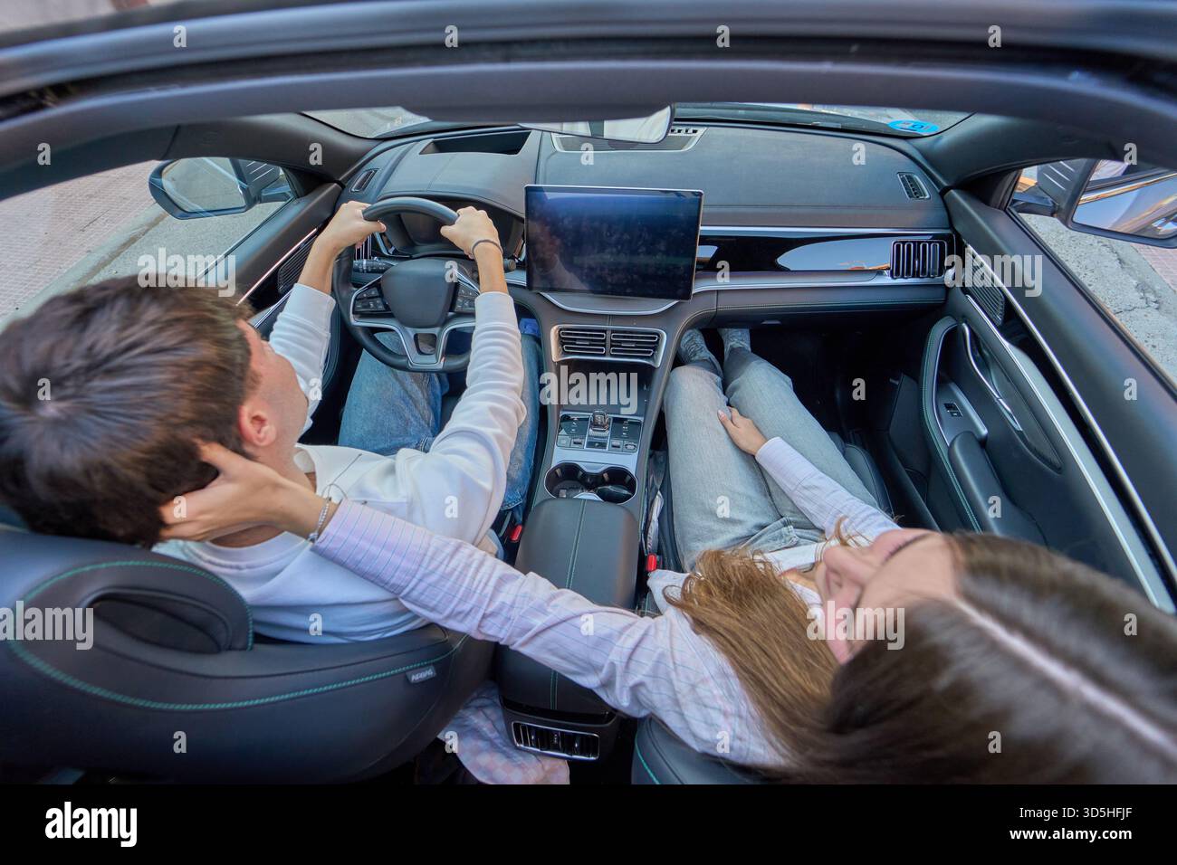 Junges Paar genießt intime Momente und romantische Verbindung in einem modernen Auto, das zusammen auf einer Roadtrip Reise unterwegs ist Stockfoto