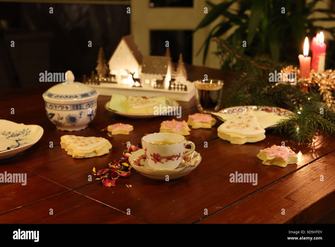 Antike Meissener Porzellan-Teetasse aus der Zeit um 1850 auf einem festlichen Weihnachtstisch mit Kerzen und hausgemachten Keksen. Stockfoto