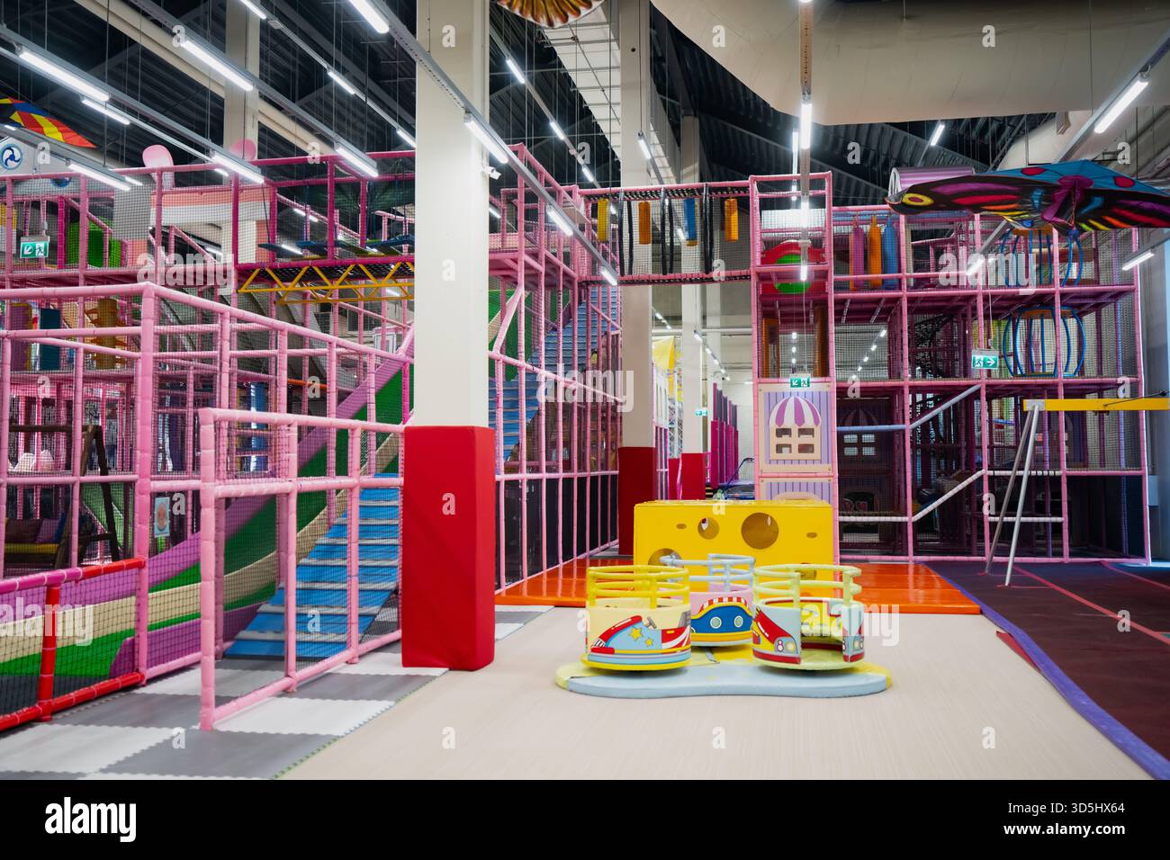Indoor-Spielplatz mit bunten Kletterrahmen, Rutschen und Spielstrukturen in einem hellen Kinderspielbereich Stockfoto