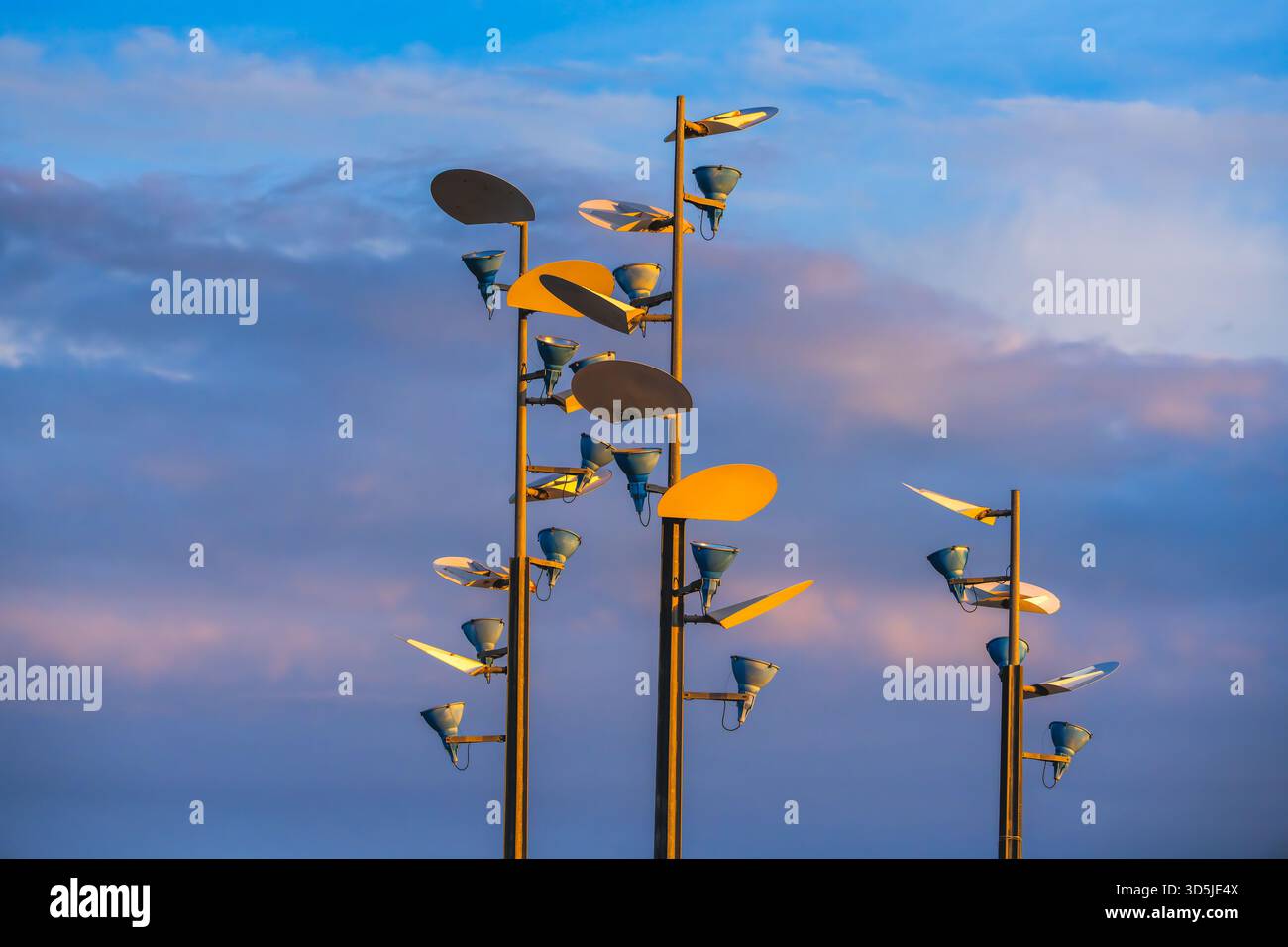 Moderne Straßenbeleuchtung mit schüsselförmigen Elementen vor einem farbenfrohen Abendhimmel Stockfoto