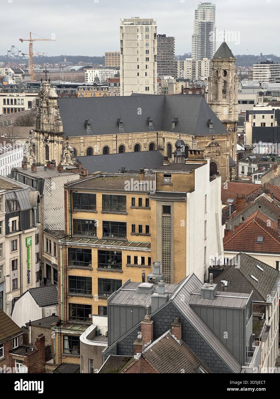 Belgien, Brüssel, 31. Dezember 2024; die Kirche saint Jean dominiert das brüsseler Stadtbild, umgeben von modernen Gebäuden und Baukränen Stockfoto