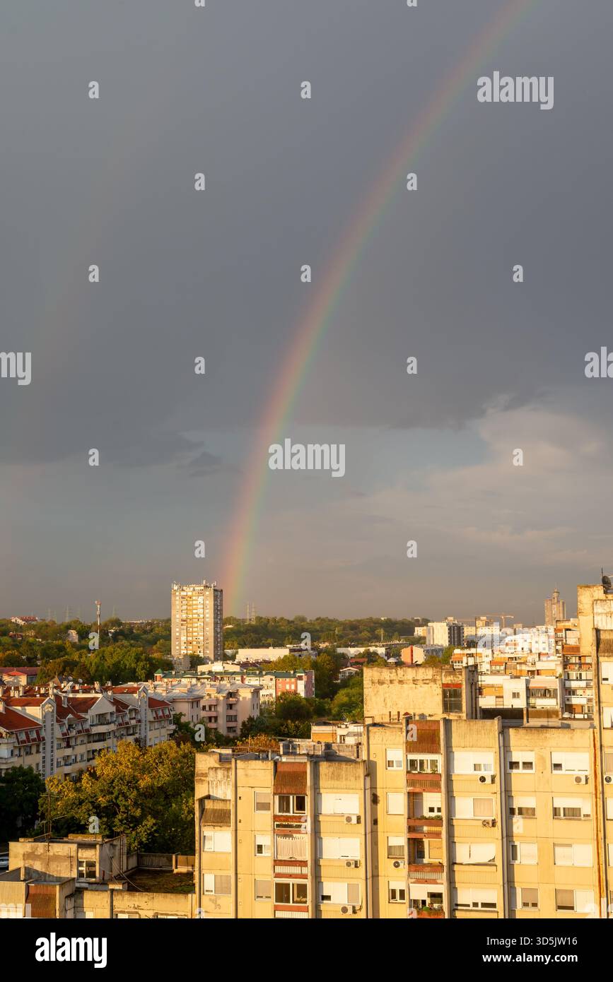 Regenbogen über städtischen Wohngebäuden nach starkem Regen an einem Tag Stockfoto