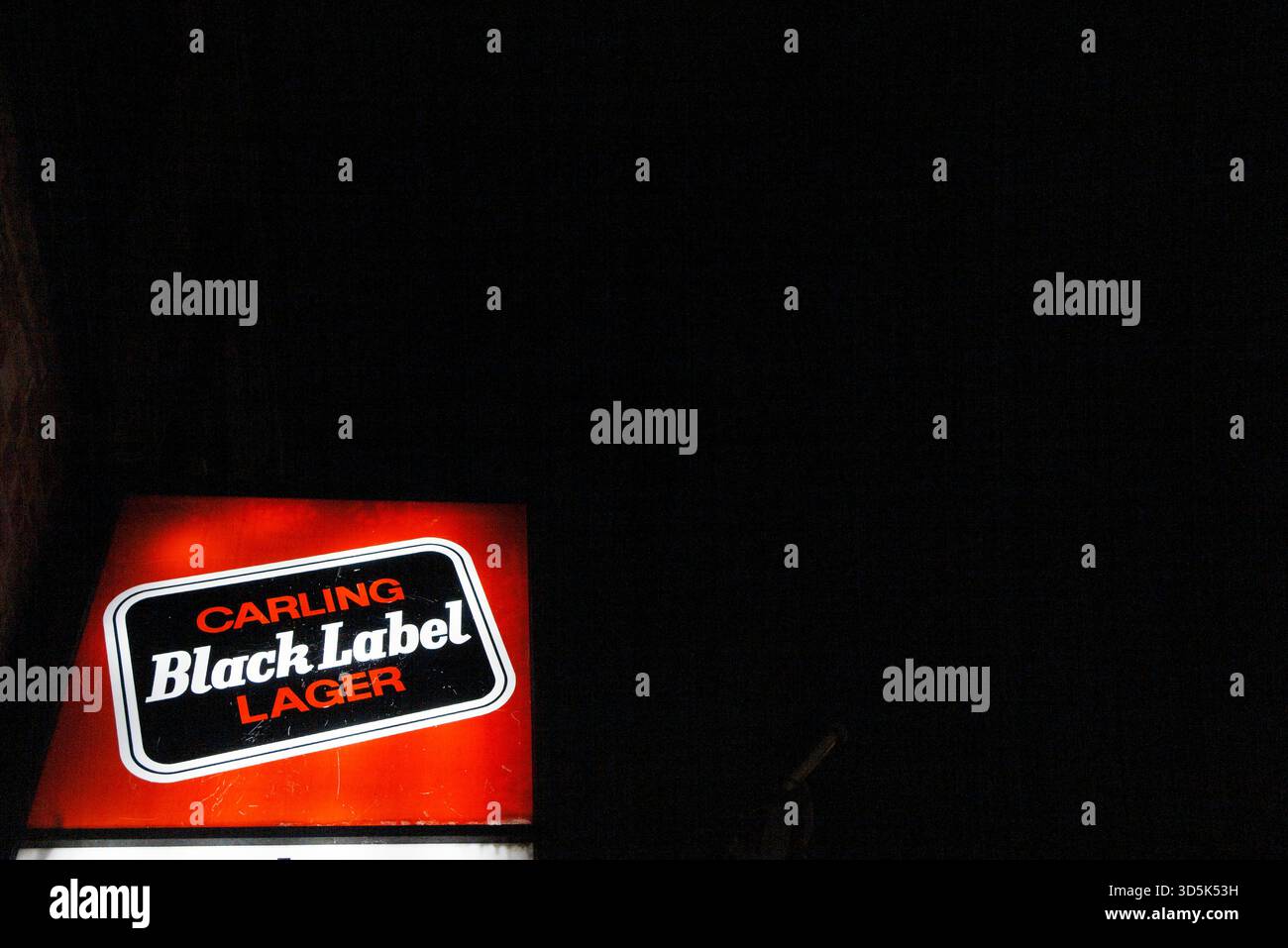 Ein traditionelles beleuchtetes Schild, das Carling Black Label Lagerbier bei Nacht anpreist Stockfoto