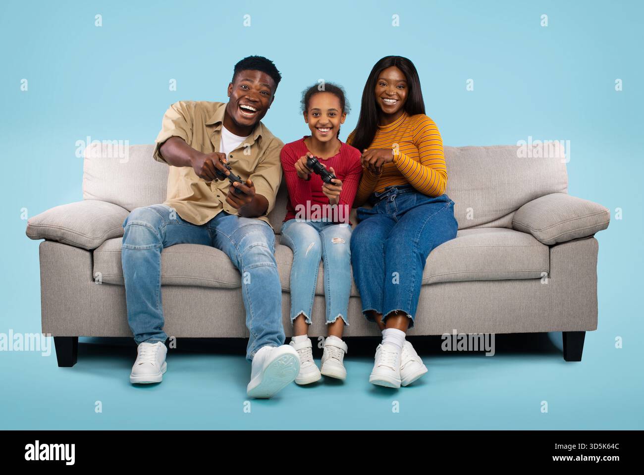 Die Familie spielt gern gemeinsam auf einer gemütlichen Couch in einer hellen, fröhlichen Umgebung Stockfoto