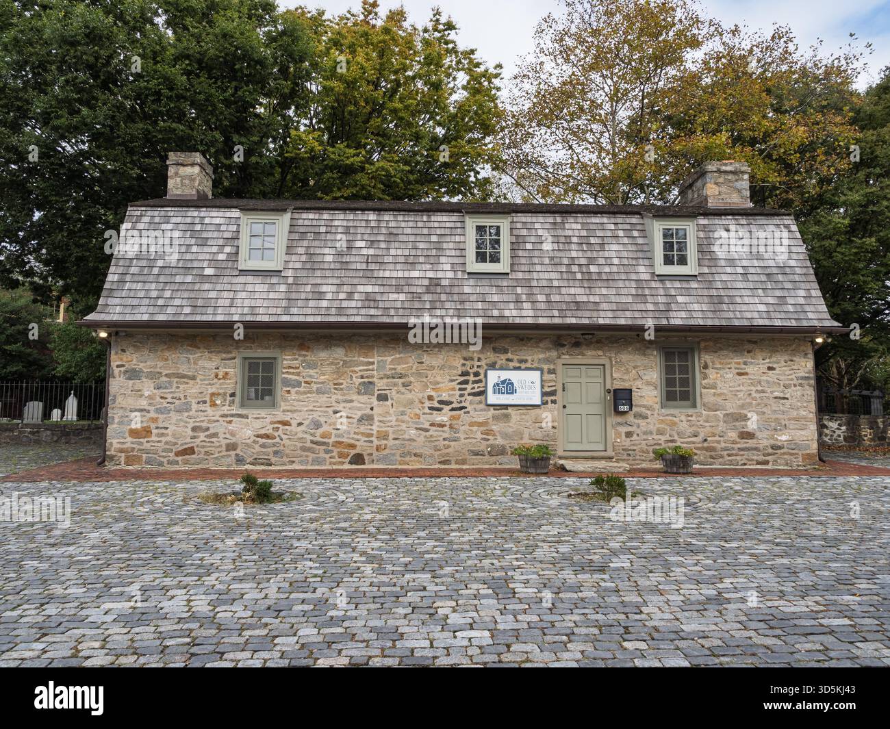 Vorderansicht des historischen Museumsgebäudes der Old Swedes Church mit einer Steinfassade, einem Holzschindeldach und einem kopfsteingepflasterten Innenhof in Wilmington, Stockfoto