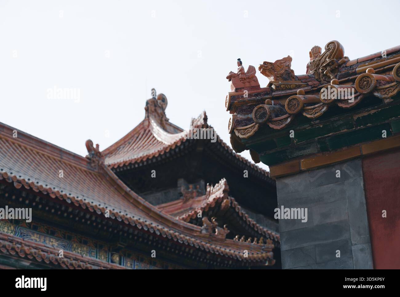 Kaiserliche Dachwächter auf glasierten Fliesen in der Verbotenen Stadt Peking mit mehrschichtigen Palastvorsprüngen vor dem Winterhimmel Stockfoto