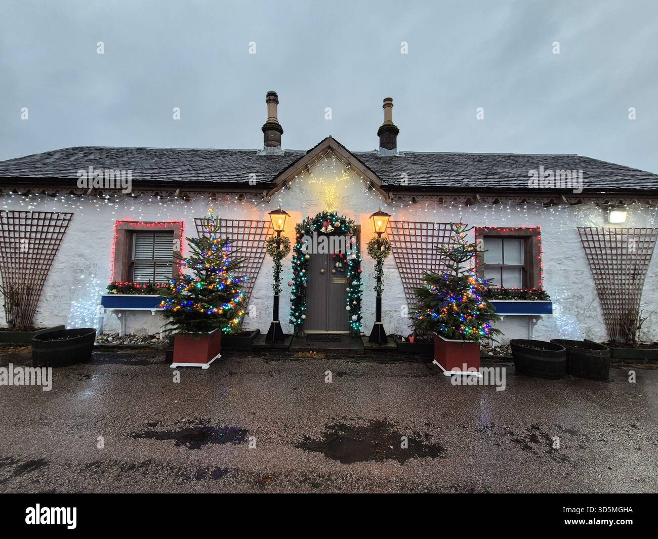Ein altes historisches Gebäude an einer Straße in Luss, Schottland. Äußere eines Cottages dekoriert für Weihnachten Stockfoto
