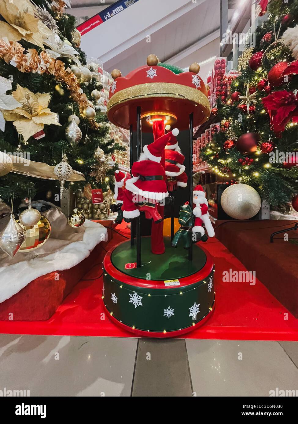 Balikpapan, Indonesien - 16. November 2025. Eine festliche, motorisierte Ausstellung mit Miniatur-Weihnachtsmannsfiguren auf einem Karussell ist von Dekor umgeben Stockfoto