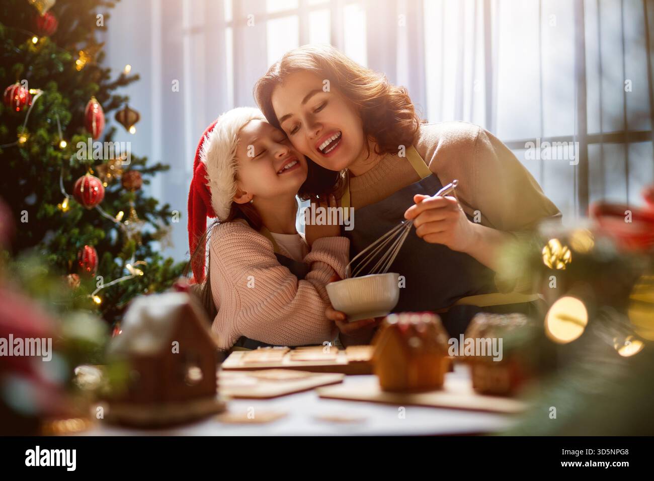 Frohe Weihnachten und frohe Feiertage. Familienzubereitung Urlaub Essen. Mutter und Tochter kochen Lebkuchenhaus. Stockfoto