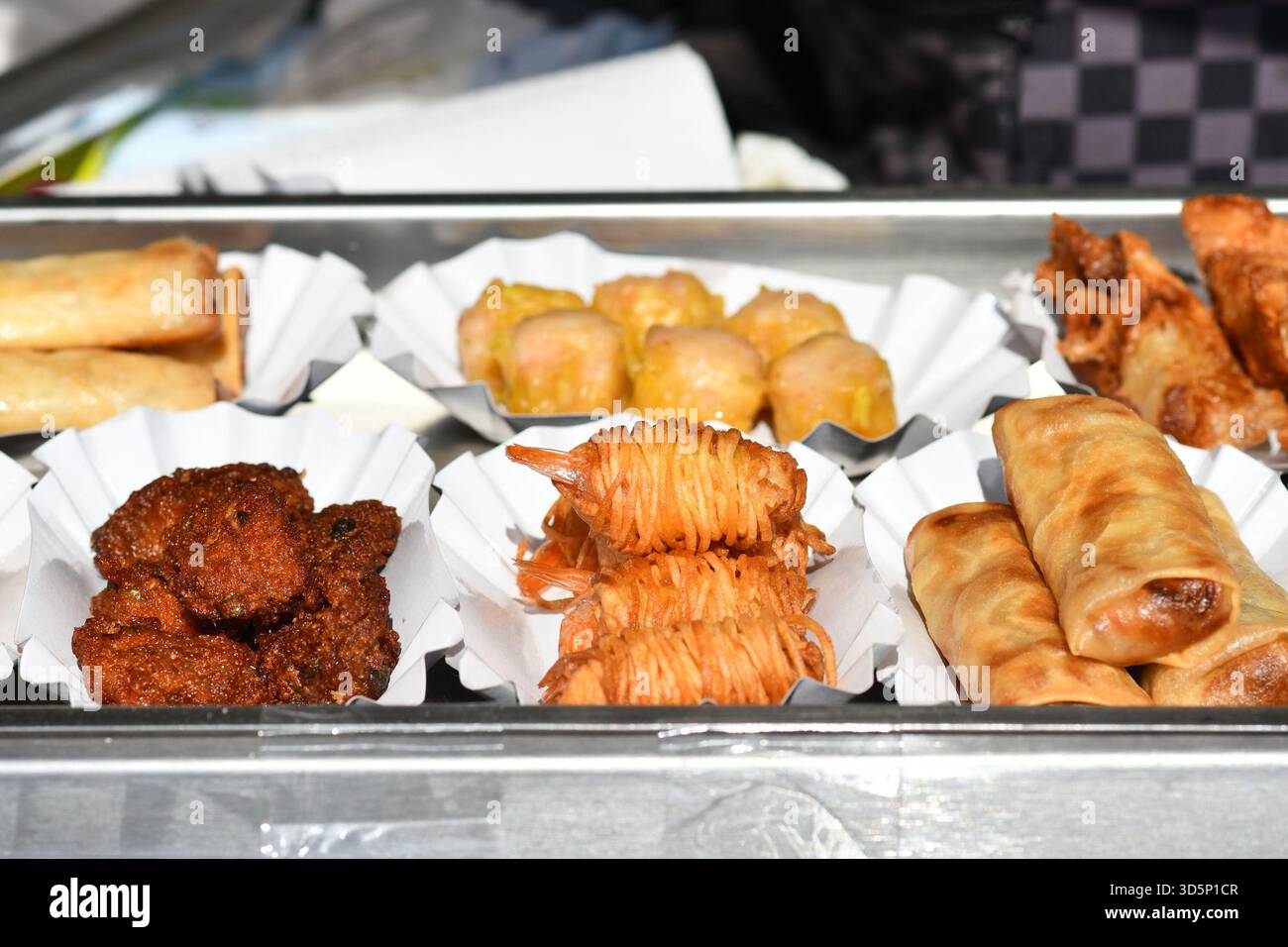 Verschiedene kleine frittierte Thai Street Food Snacks wie Frühlingsrollen oder Kartoffelnudelgarnelen auf kleinen Tabletts Stockfoto