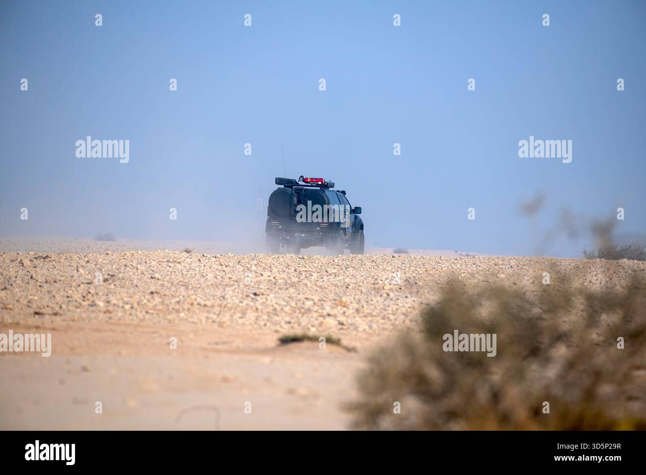 Doha, Katar - 14. November 2025: Ein stark modifizierter Geländewagen fährt durch ein felsiges Wüstengelände und wirft hinter seinem großen All-ter Staub auf Stockfoto